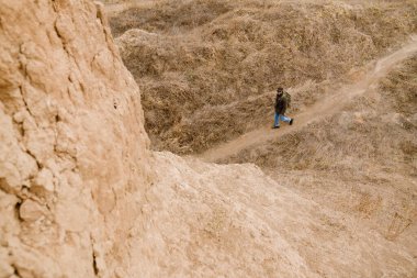 Güneş gözlüklü genç fotoğrafçı dışarıda dijital kamerayla yürüyor.