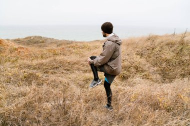 Sahilde çalışırken egzersiz yapan yakışıklı bir adam.