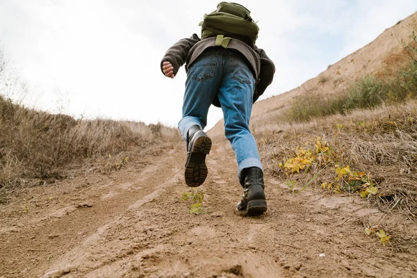 Man climbing on hill with backpack outdoors