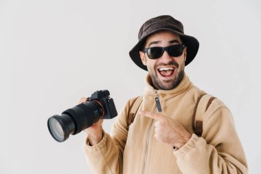 Beyaz arka planda izole edilmiş dijital kamerayı gösteren mutlu fotoğrafçı.