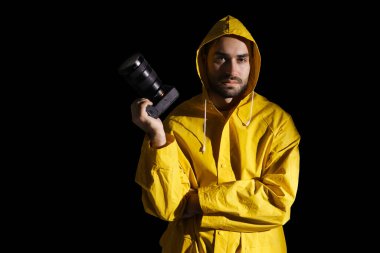 Siyah arkaplan üzerinde dijital kamerayla poz veren ciddi fotoğrafçı