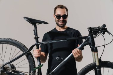 Beyaz arka planda izole edilmiş bisikletiyle poz verirken gülümseyen mutlu genç binici.