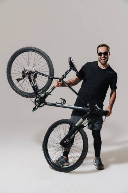 Heyecanlı genç binici, beyaz arka planda izole edilmiş bisikletiyle poz verirken gülümsüyor.