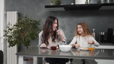 Pozitif anne ve kız kahvaltı yapıyorlar evdeki mutfaktaki masada oturuyorlar.