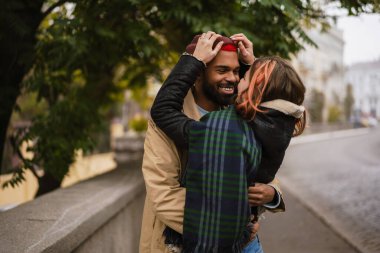 Çok uluslu, güzel, mutlu bir çift şehrin caddesinde dururken sarılıp gülümsüyor.