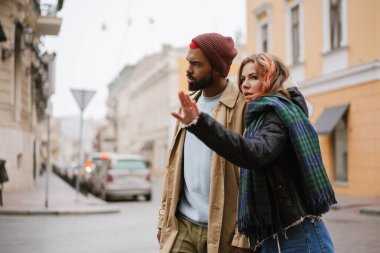 Çok uluslu güzel, ciddi bir çift şehir caddesinde yürürken el ele tutuşuyor.