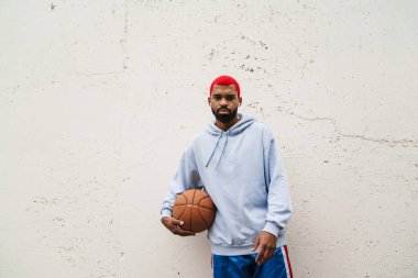 Kulaklıklı, kendine güvenen Afro-Amerikan adam dışarıda basketbol oynuyor.