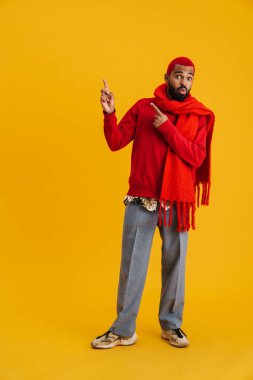 Eşarplı afro-amerikan adam sarı arka planda, parmaklarını yukarı kaldırdı.