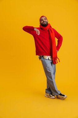 Rahatlamış genç Afrikalı bir adamın portresi. Sarı bir duvara yaslanmış, uzun boylu.