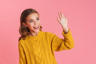 Mutlu güzel sarışın kız gülümsüyor ve pembe arka planda el sallıyor.