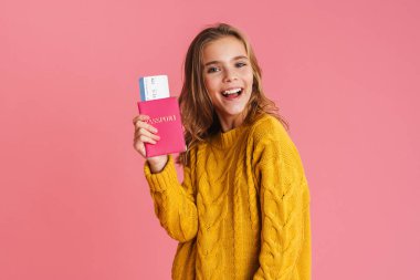 Pasaportu pembe arka planda izole edilmiş mutlu, güzel sarışın kız gülümsüyor.