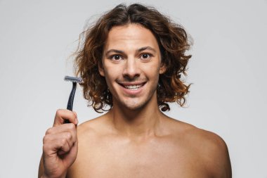 Beyaz arka planda jiletle poz verirken gülümseyen, neşeli, üstsüz, yakışıklı adam.