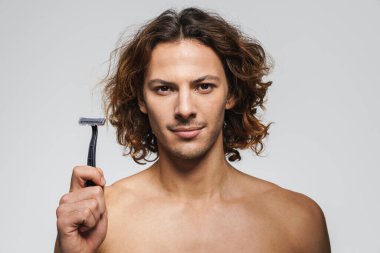 Beyaz arka planda jiletle poz veren kendinden emin, yakışıklı adam.