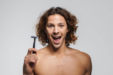 Heyecanlı üstsüz yakışıklı adam beyaz arka planda jiletle poz veriyor.