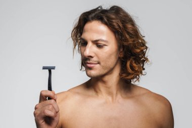 Beyaz arka planda jiletle poz veren ciddi, üstsüz, yakışıklı bir adam.