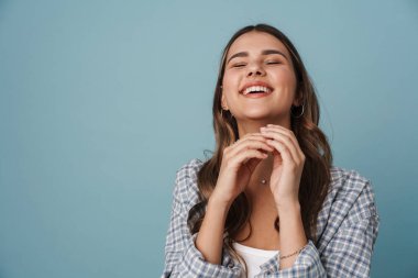 Mutlu güzel kız mavi arka planda izole edilmiş kameraya gülüyor ve poz veriyor.