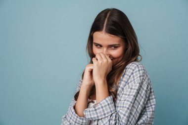 Mutlu, güzel, mütevazı kız gülümseyen ve aşağıya bakan, mavi arka planda soyutlanmış.