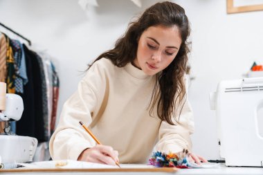 Atölyede çalışırken güzel esmer kız terzilik işine odaklanmış.