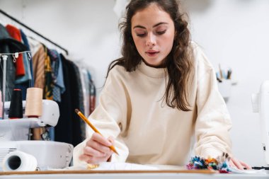 Atölyede çalışırken güzel esmer kız terzilik işine odaklanmış.