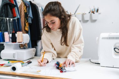 Atölyede çalışırken güzel esmer kız terzilik işine odaklanmış.