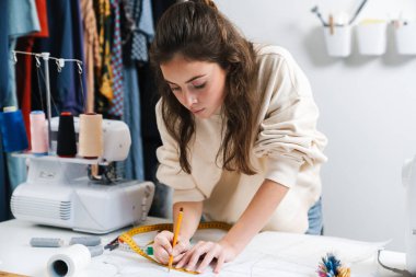 Atölyede çalışırken güzel esmer kız terzilik işine odaklanmış.