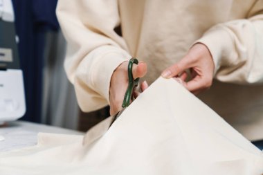 Atölyede çalışırken kumaş kesen beyaz, hoş bir kız.