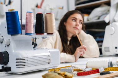 Atölyede dikiş dikerken konsantre olmuş terzinin portresi.