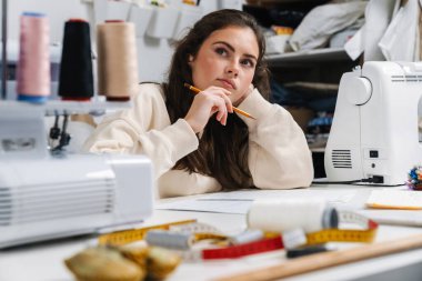Atölyede dikiş dikerken konsantre olmuş terzinin portresi.