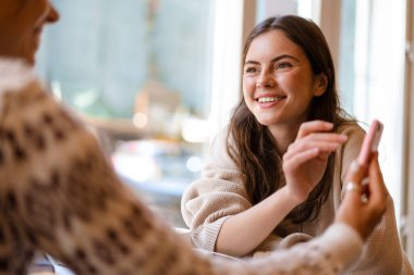 Cafe 'de kahve içerken cep telefonu kullanan mutlu iki kız.