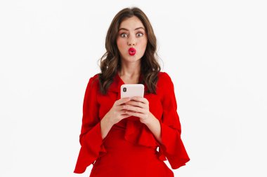 Kırmızı elbiseli, beyaz arka planda izole edilmiş cep telefonu kullanan güzel bir kız.