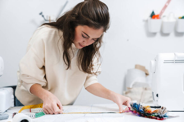 Portrait of concentrated seamstress sewing in the workshop studio