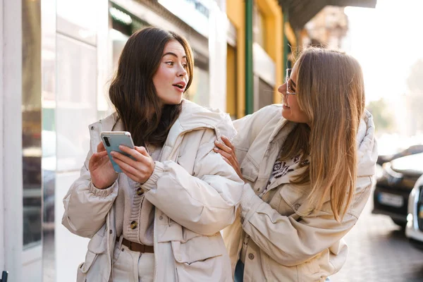 Happy young woman greeting her girlfriend on a street