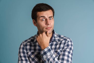 Mavi arka planda izole edilmiş düşünceli genç adam.