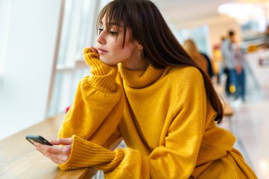 Masada otururken cep telefonu kullanan çekici bir kız.