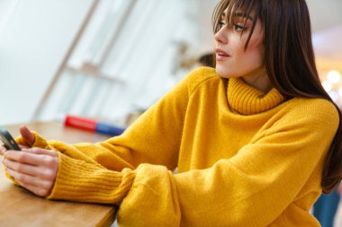 Masada otururken cep telefonu kullanan çekici bir kız.