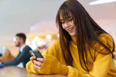 Masada otururken cep telefonu kullanan güzel bir kız.