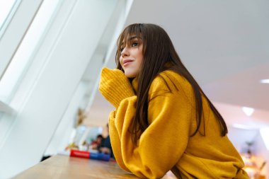 Çekici, mutlu, gülümseyen ve pencereden dışarı bakan bir kız.