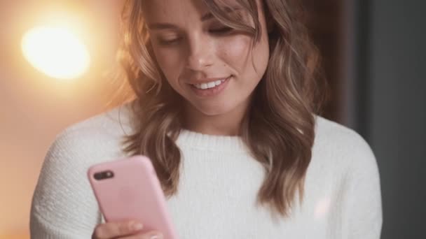 Una Mujer Sonriente Está Usando Teléfono Inteligente Sosteniéndolo Mano Mientras — Vídeos de Stock