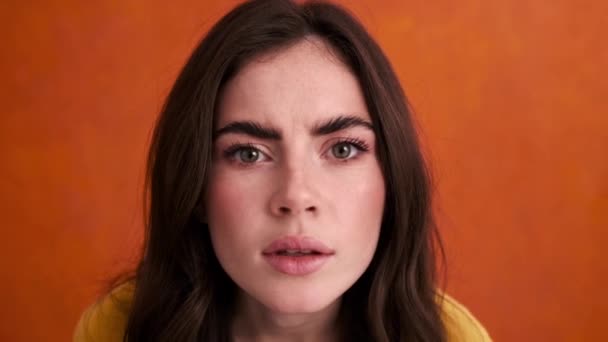 Удивлённая Молодая Женщина Смотрит Глазок Изолированный Оранжевом Фоне Студии — стоковое видео