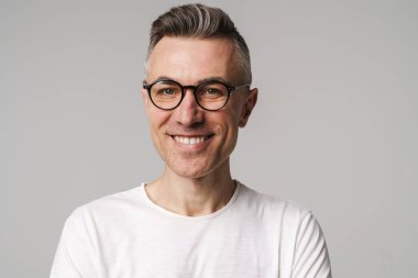 Gri arka planda izole edilmiş mutlu, güler yüzlü, kendine güvenen bir adamın portresi