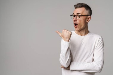 Gri arkaplanda izole edilmiş kopya alanı sunan heyecanlı genç adam