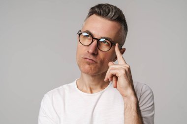 Gri arka planda izole edilmiş düşünceli bir adamın portresi.