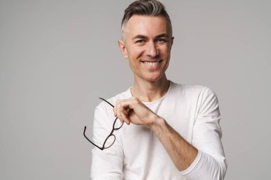 Gri arka planda izole edilmiş mutlu, güler yüzlü, kendine güvenen bir adamın portresi