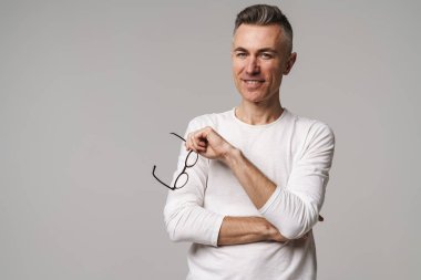 Gri arka planda izole edilmiş mutlu, güler yüzlü, kendine güvenen bir adamın portresi