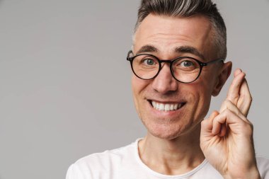 Endişeli gülen adam gri arka planda bir dilek diliyor.