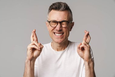 Endişeli gülen adam gri arka planda bir dilek diliyor.