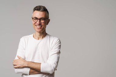 Gri arka planda izole edilmiş mutlu, güler yüzlü, kendine güvenen bir adamın portresi