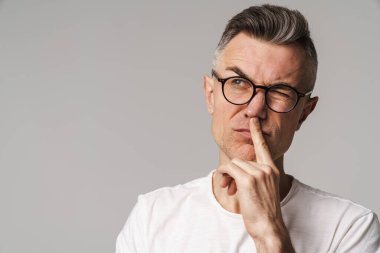 Gri arka planda soyutlanmış düşünen şüpheci bir adamın portresi.