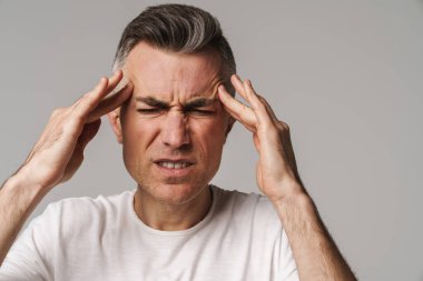 Endişeli adam baş ağrısı çekiyor. Gri arka planda izole edilmiş.