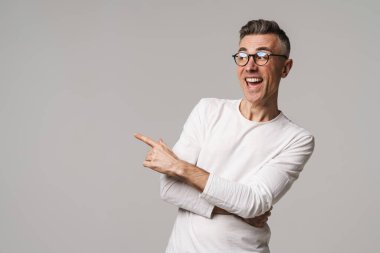 Gri arkaplanda izole edilmiş kopya alanı sunan heyecanlı genç adam